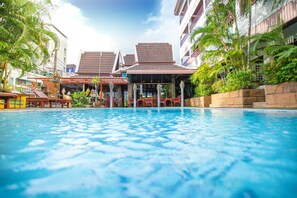 Une piscine avec vue sur un immeuble doté d’un toit en tuiles et de balcons.