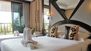 A neatly made bed with white linens and decorative pillows, a large window with curtains, and a view of greenery outside. - Kelly’s Residency (Patong)