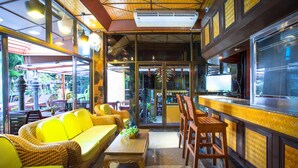 A restaurant interior with wicker furniture, a bar area, and large windows. - Kelly’s Residency (Patong)