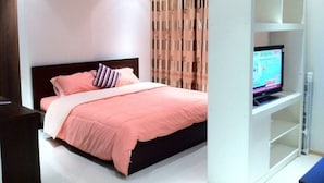 Ein modernes Schlafzimmer mit einem Bett, einem Fernseher auf einem Schrank und einem weißen Regalelement.