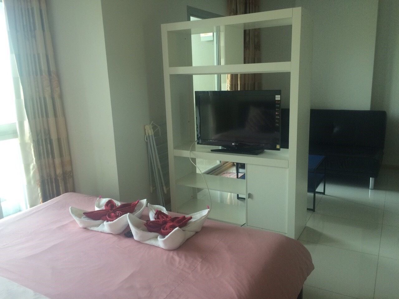 Une chambre d’hôtel avec un lit, un téléviseur posé sur un meuble et un bureau avec une chaise.