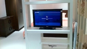 Ein Zimmer mit einer weißen Unterhaltungsecke, in der sich ein Flachbildfernseher befindet.