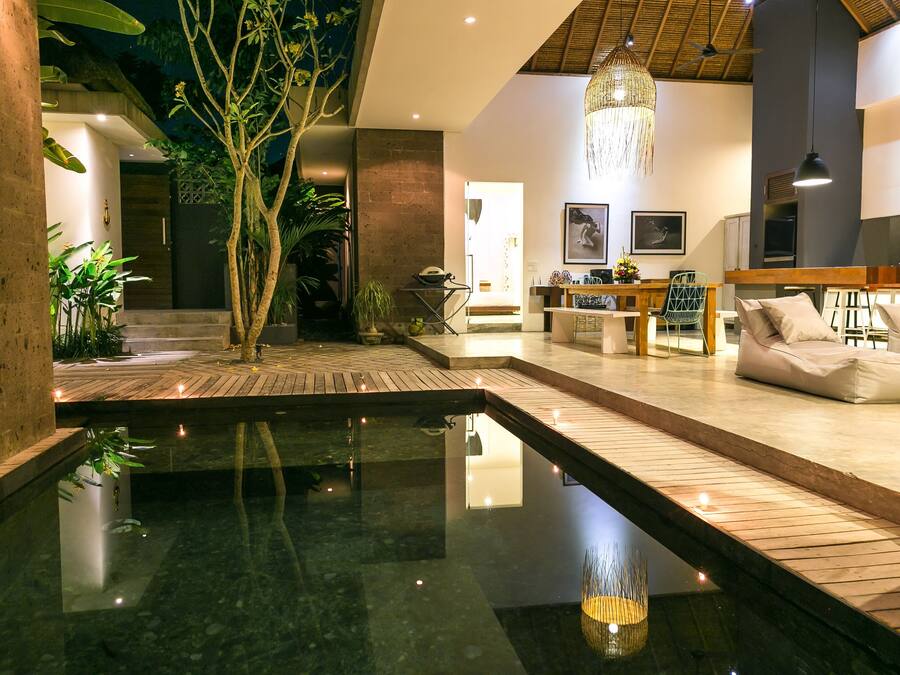 Un interior moderno con una fuente central, suelo de madera y un área de descanso con cojines.