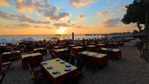 A beachside restaurant with outdoor seating and tables set for dining. - Sri Kandi Inn (Kedonganan)