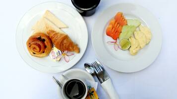 Deux assiettes de nourriture, une tasse de café, une fourchette et une cuillère, le tout posé sur une nappe blanche.