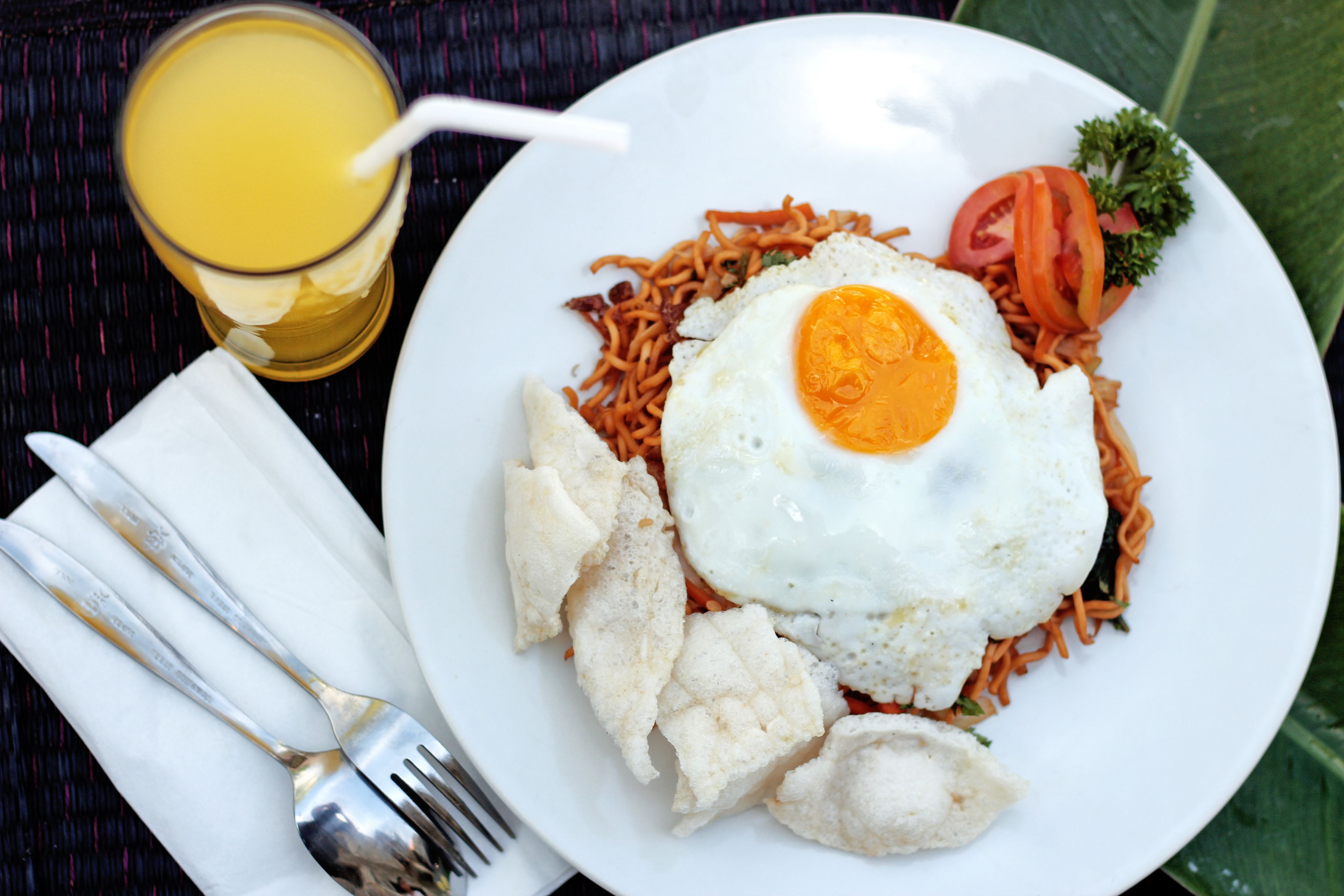 A plate of food with noodles, a fried egg, and vegetables.