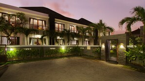 A hotel with a paved courtyard, multiple balconies, and palm trees. - Sri Kandi Inn (Kedonganan)
