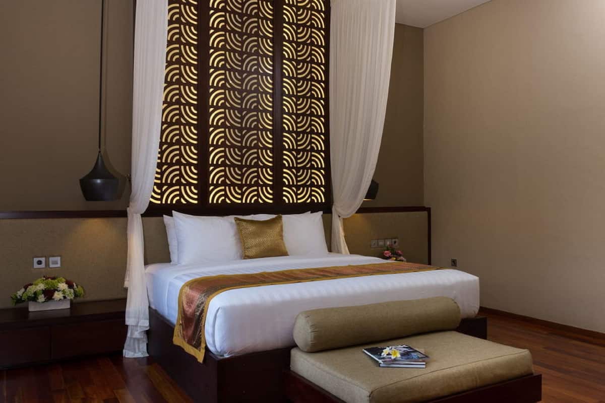 Une chambre à coucher avec un lit à baldaquin, des tables de chevet, une petite table de nuit et un petit coin salon.
