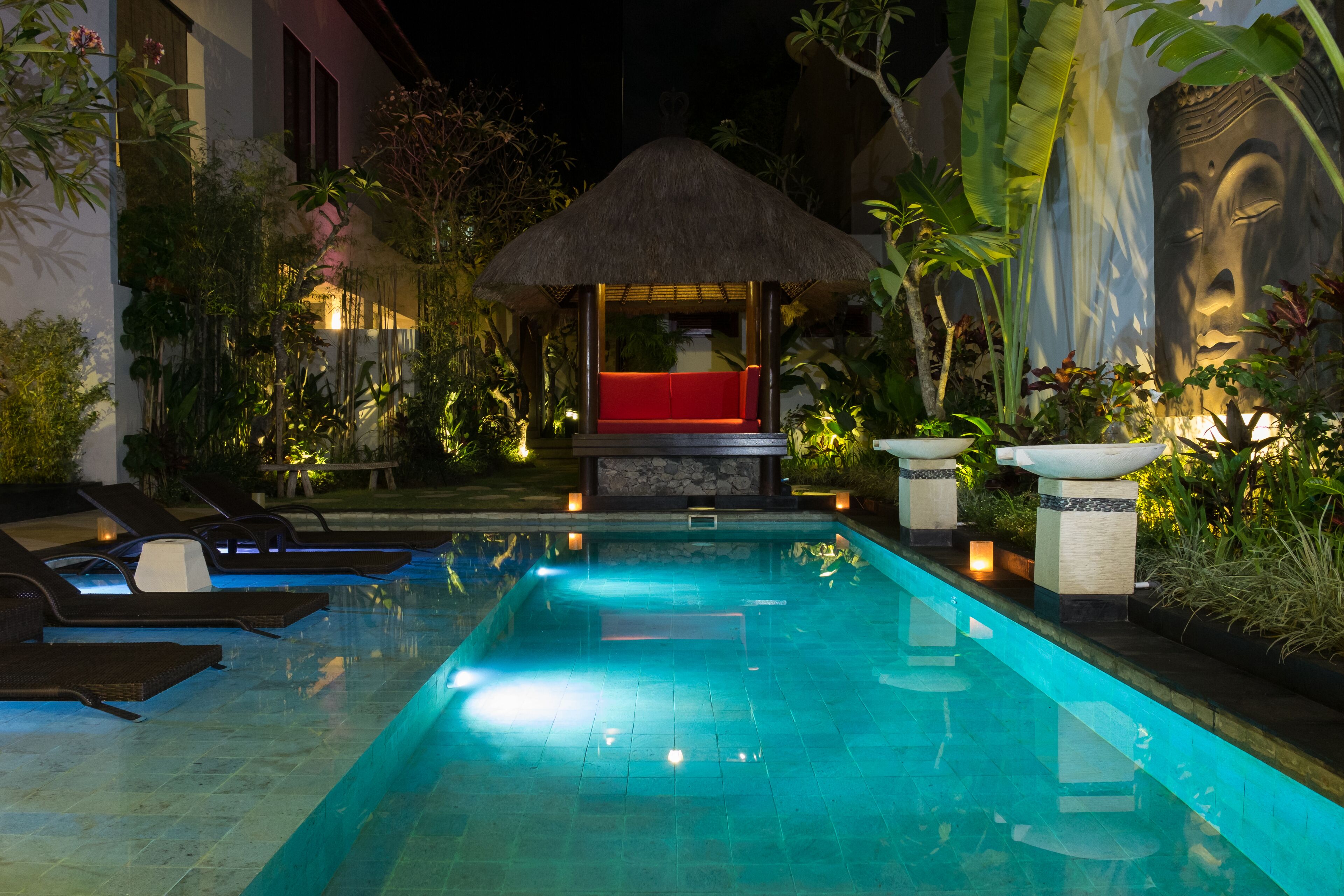 A swimming pool with lounge chairs and a thatched-roof structure.