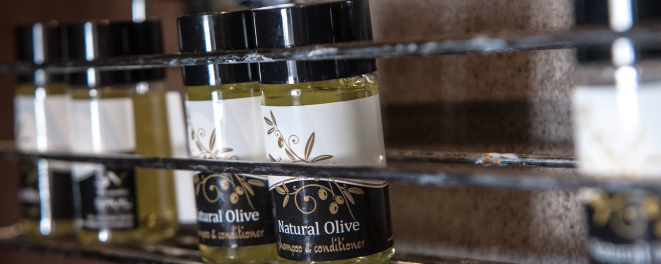 Estante com várias garrafas de Shampoo e Condicionador de Azeitona Natural.