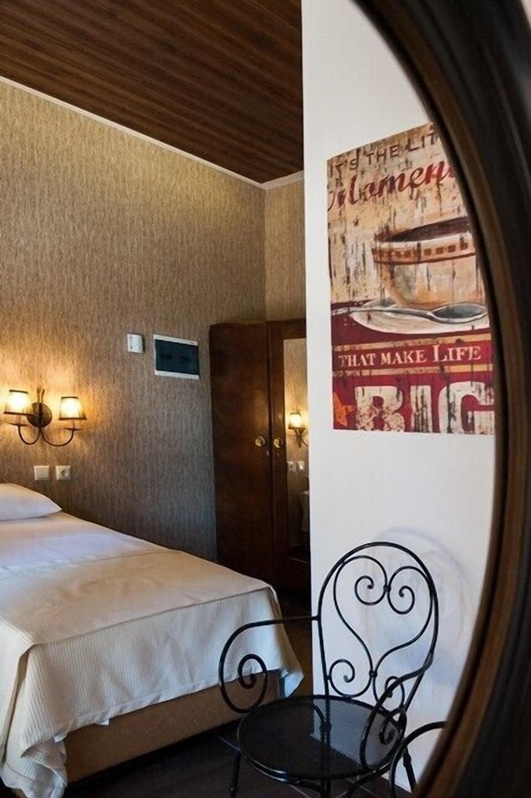 Una habitación de hotel con una cama, una silla, una lámpara de pared y un cartel.
