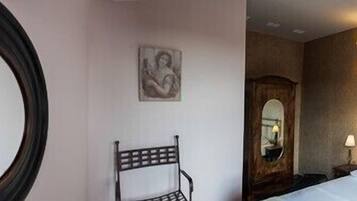 Habitación de hotel con cama, mesita de noche, espejo y dos sillas.
