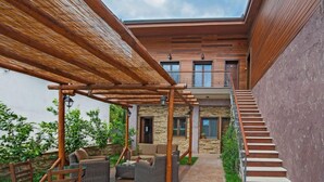 A modern house with a stone exterior, a wooden staircase, and outdoor furniture. - Polys Guest House (Pydna-Kolindros)