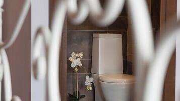 A bathroom with a toilet and a decorative orchid plant.