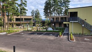 A parking lot with designated handicapped spaces, a building with a green facade, and a staircase leading to an upper level. - Hotell Fritidsparken (Skien)