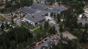 An aerial view of a town with a large building complex, parking areas, and surrounding greenery. - Hotell Fritidsparken (Skien)