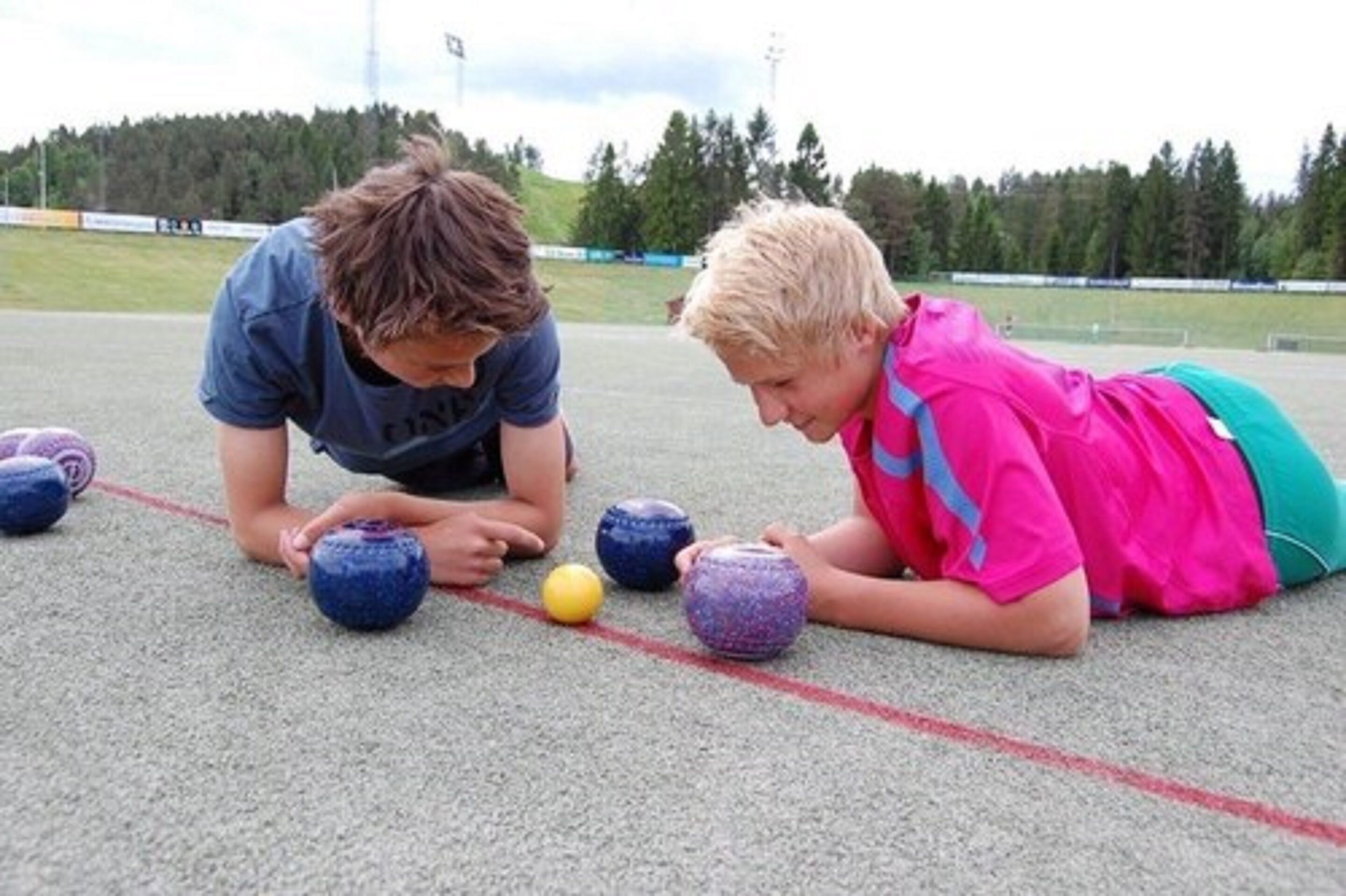 Duas pessoas brincando com bolas em uma quadra esportiva.