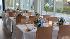A restaurant with multiple tables set for dining, each with wine glasses, bottles, and cutlery. - Hotell Fritidsparken (Skien)