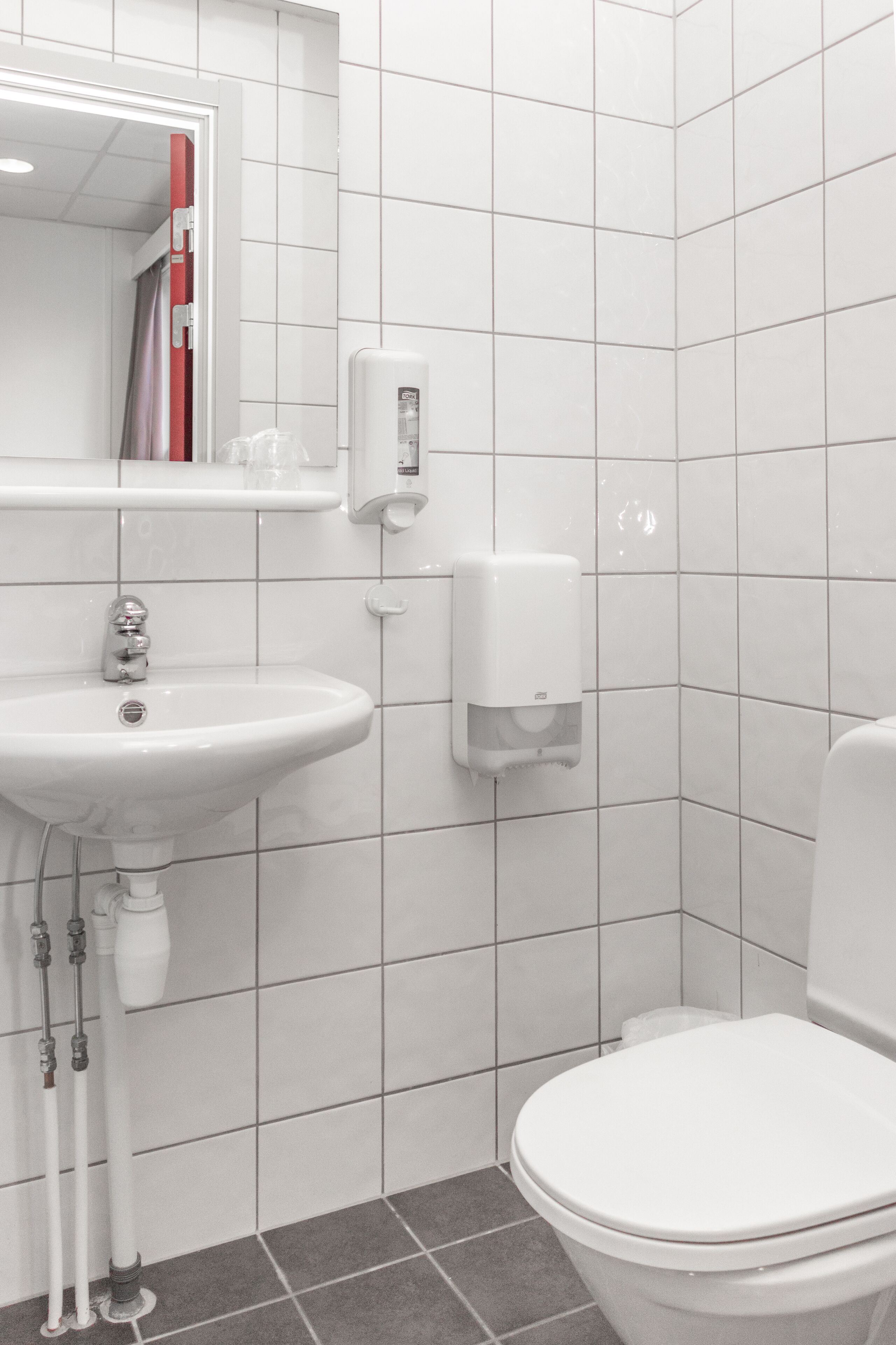 Un baño con lavamanos, espejo y retrete blancos.