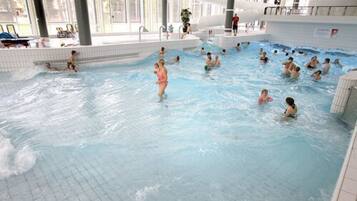 Una piscina cubierta con varias pistas, agua cristalina y suelo de baldosas.