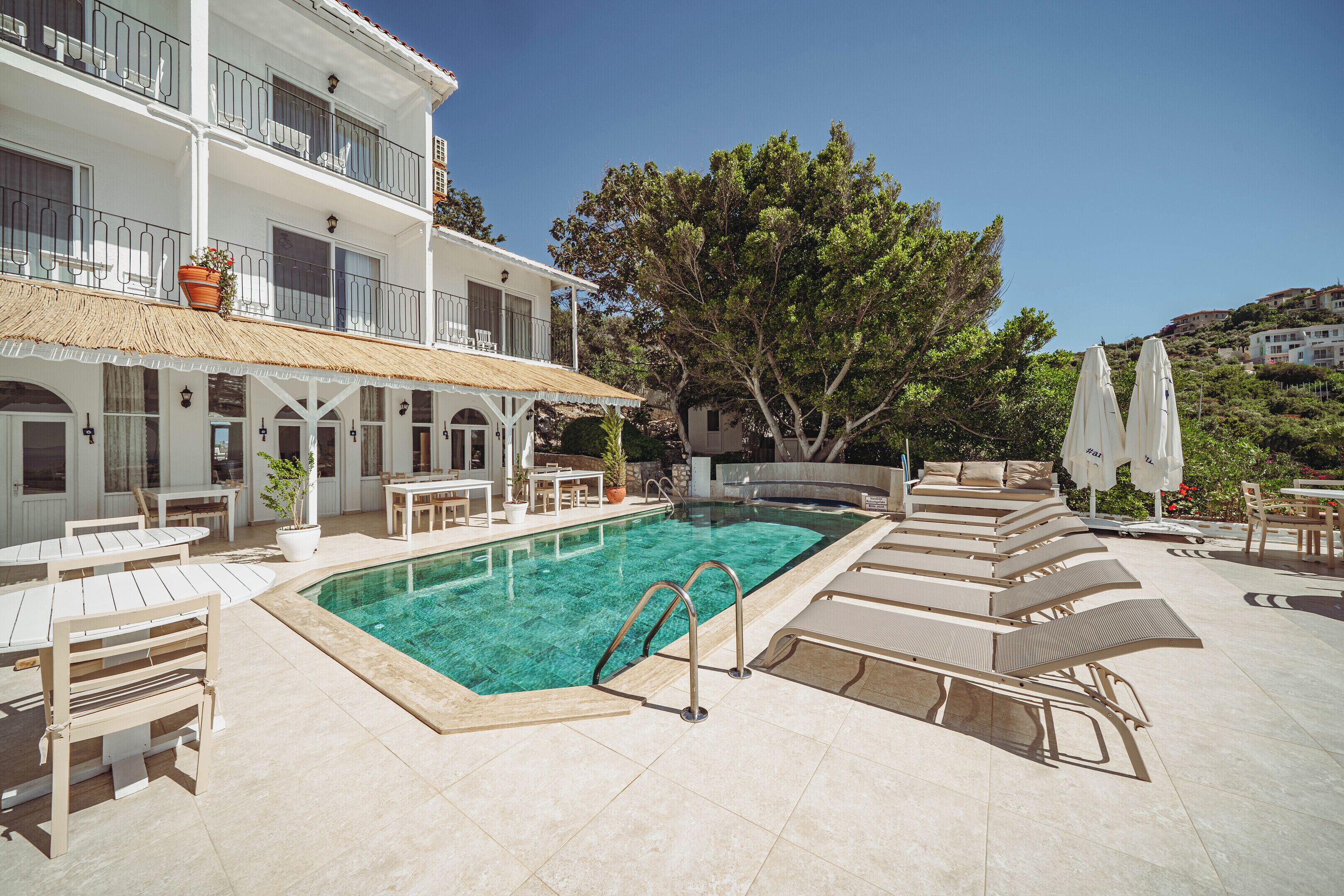 Un área de piscina con sillones de descanso, un jacuzzi y un comedor.