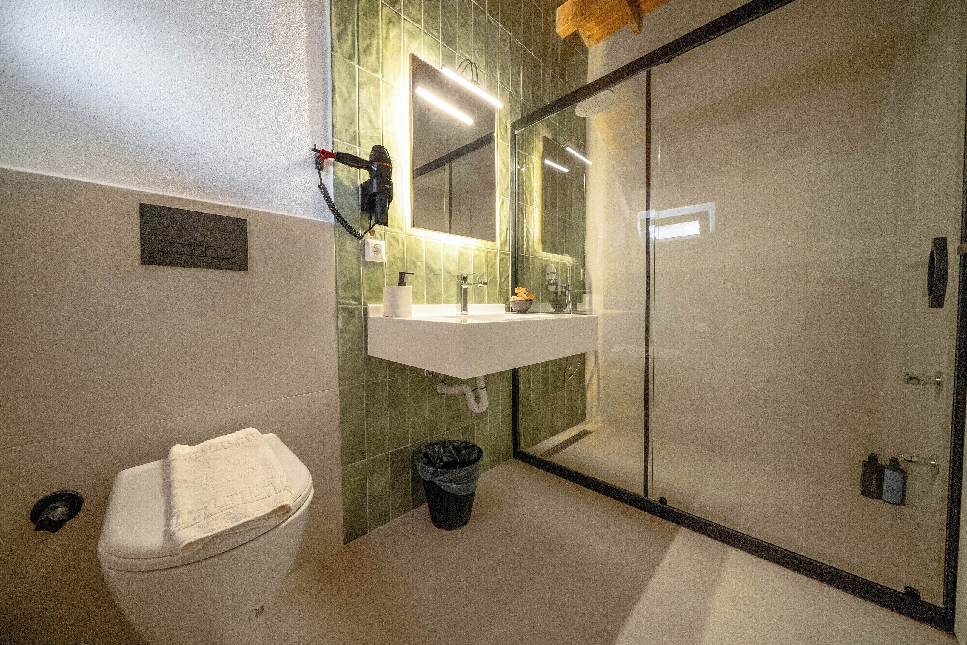 Une salle de bain comprenant des toilettes, un lavabo et un espace douche.