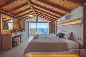 A bedroom with a large bed, a desk, and a view of the sea. - Arpia Hotel (Kas)