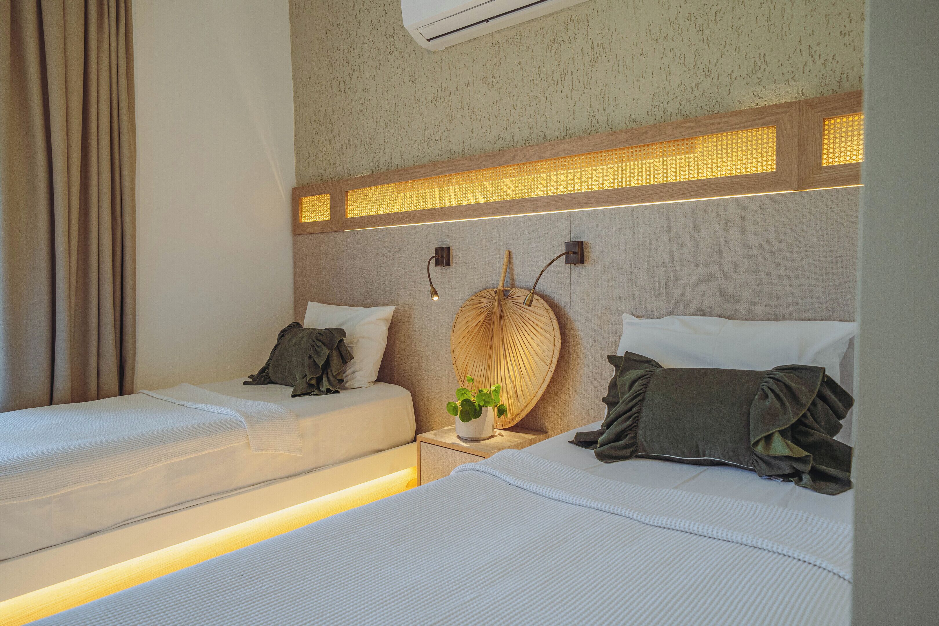 Habitación de hotel con dos camas, una lámpara de pared y una planta en maceta.