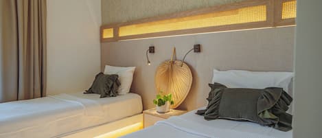 Habitación de hotel con dos camas, una lámpara de pared y una planta en maceta.