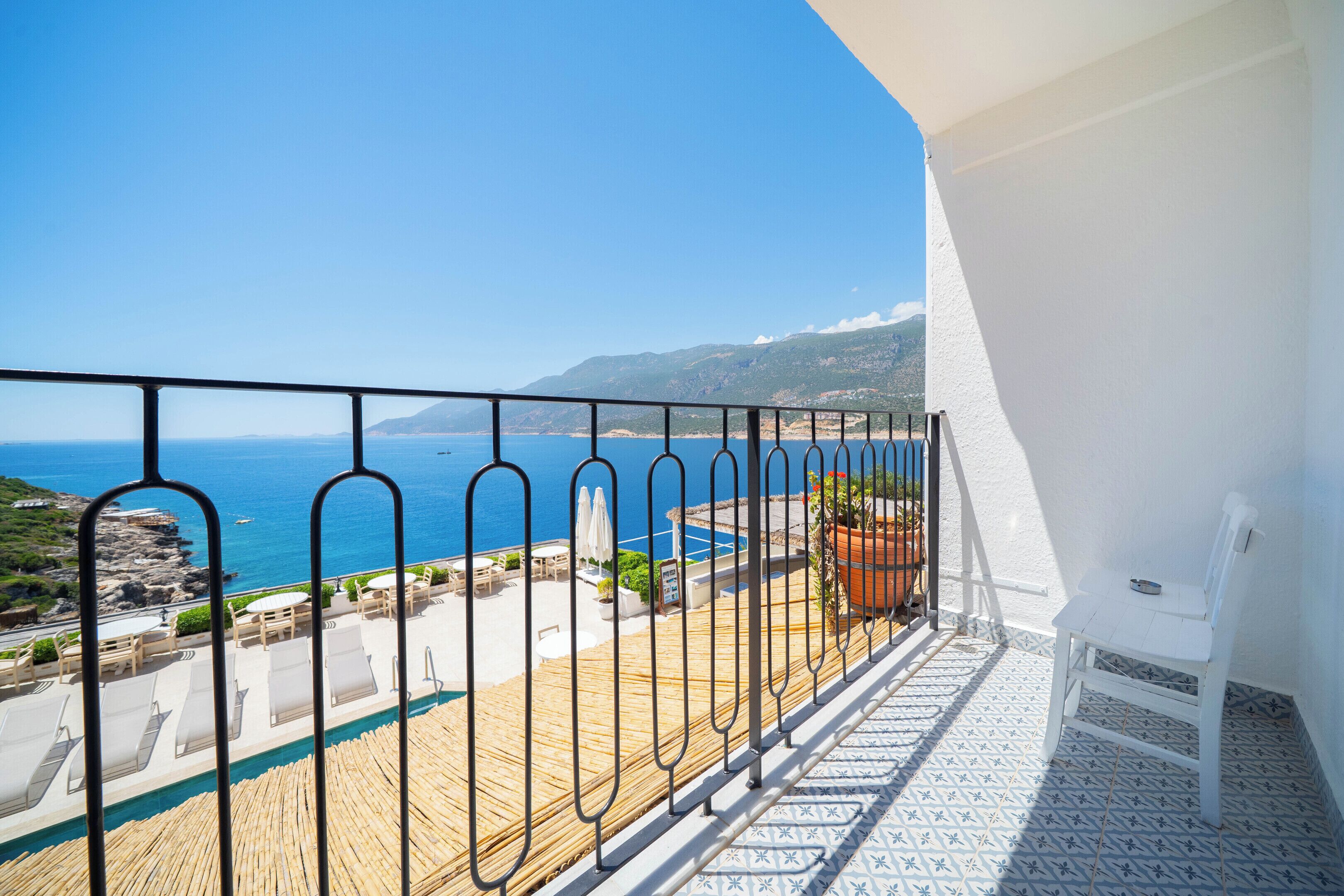 Un balcón con vista al mar, una piscina y una silla.