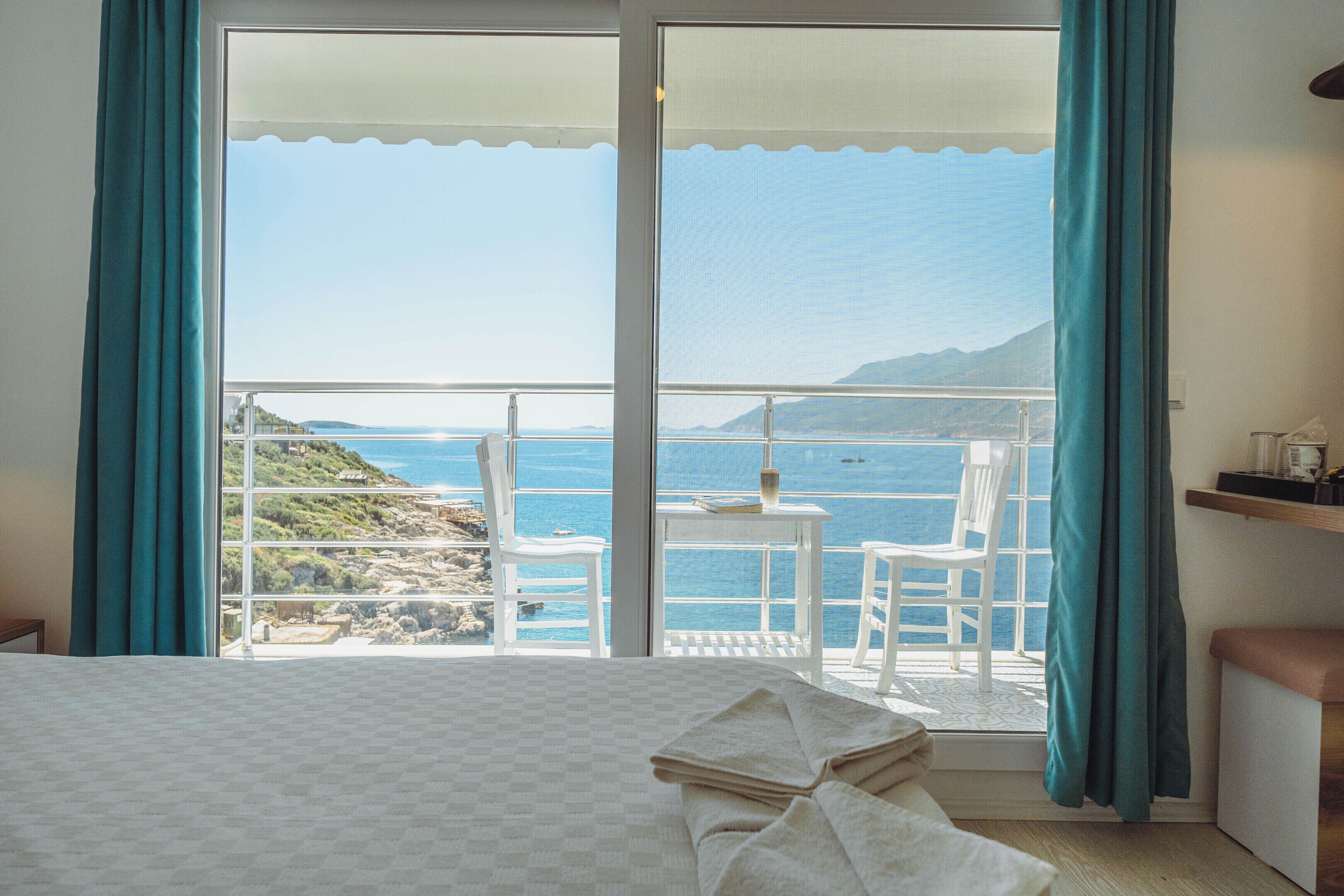 Habitación de hotel con una cama, una mesa con una silla y vistas al mar y a las montañas.