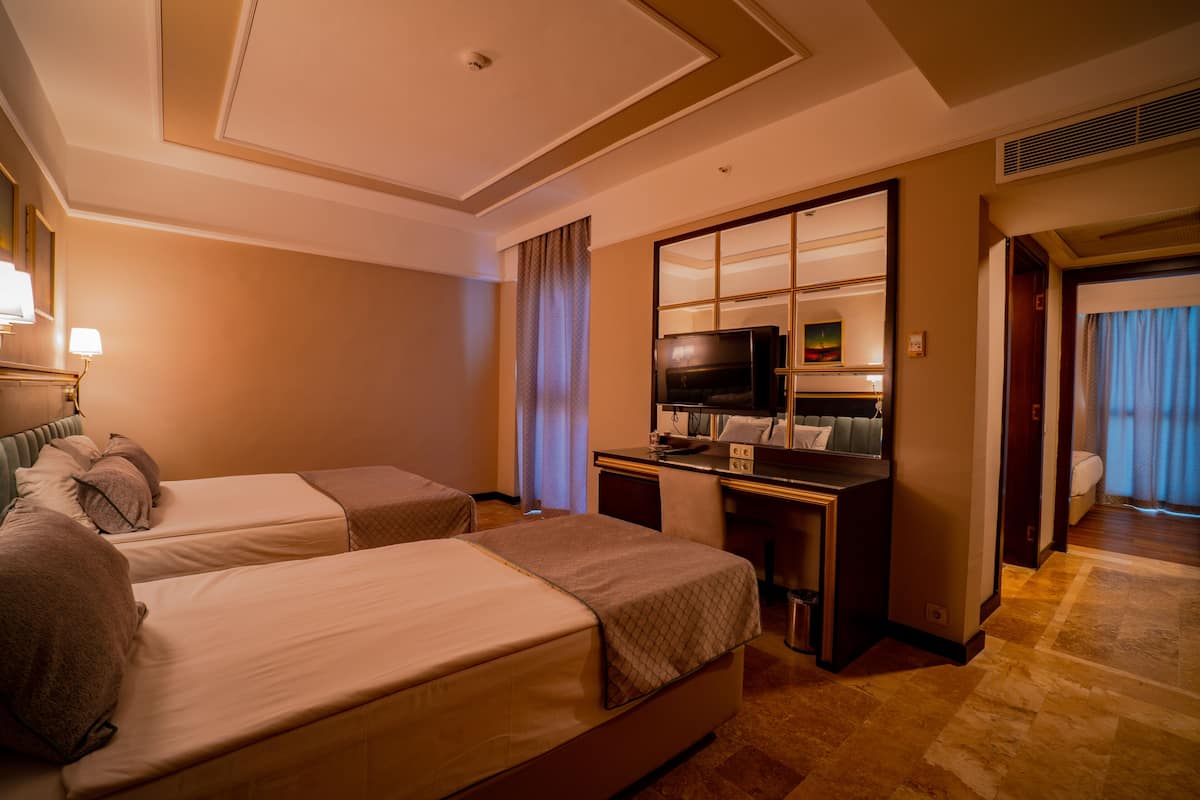 A hotel room with two beds, a desk with a television, and a bathroom visible through an open door.