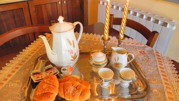 A tray with pastries, a teapot, cups, and a candle holder on a table with a lace tablecloth.