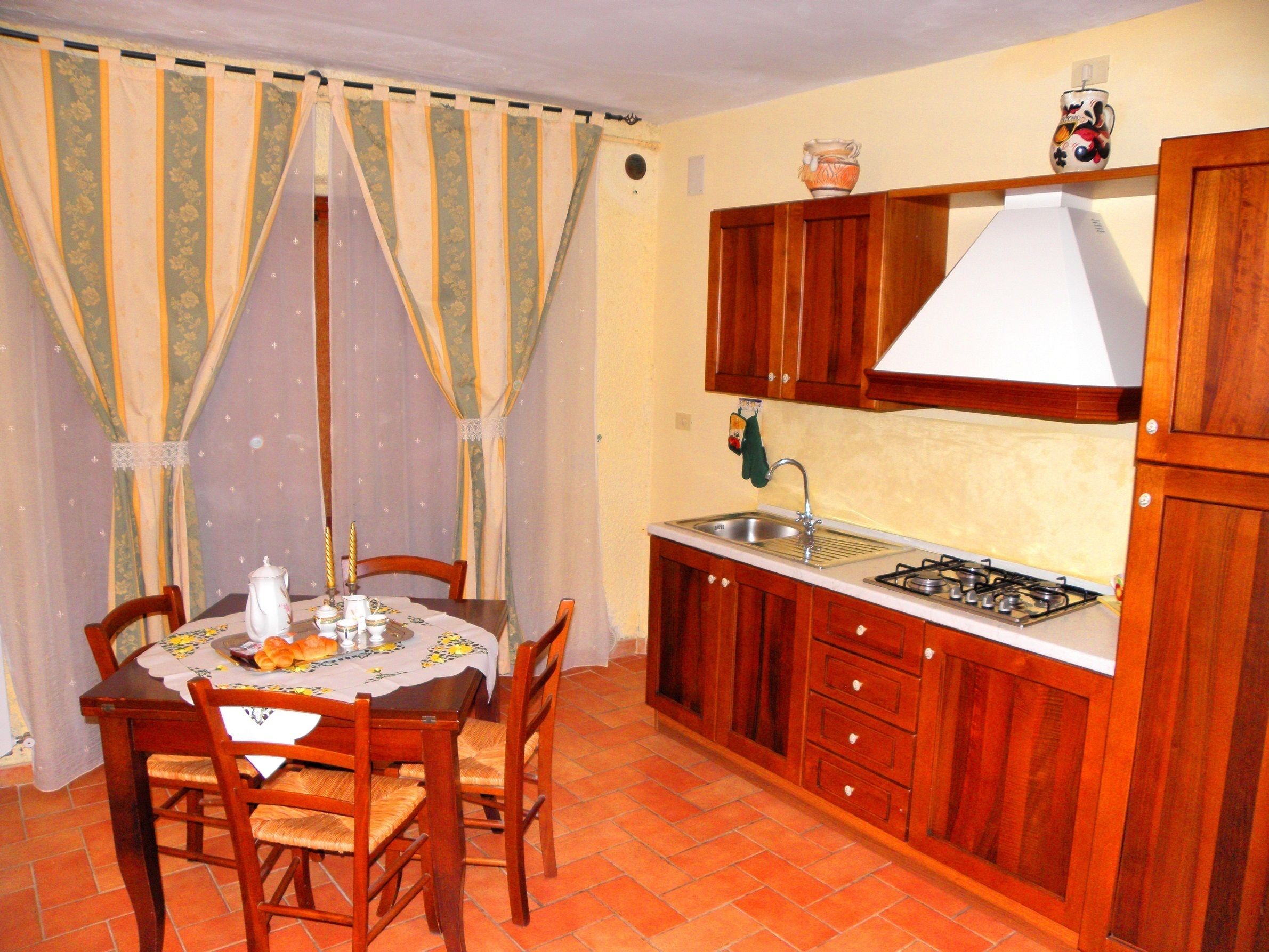 Una cocina funcional con muebles de madera, estufa a gas y pileta.