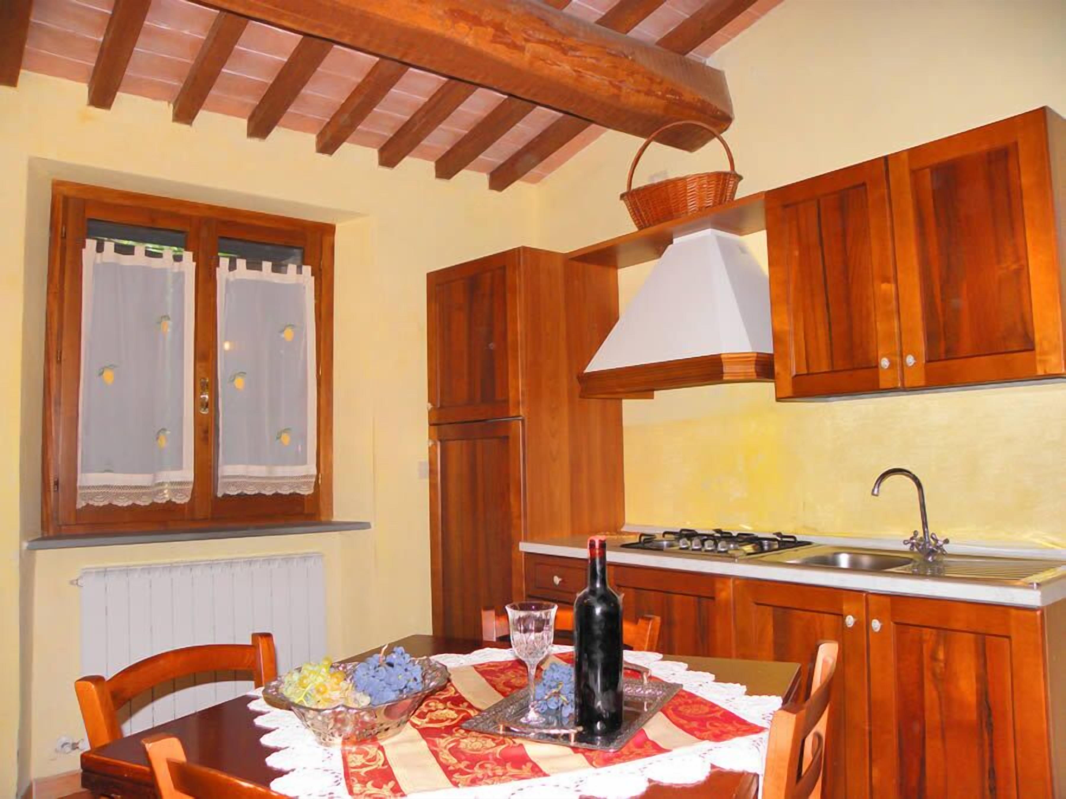 A kitchen with wooden cabinets, a table with a placemat, a bottle, and a basket on the counter.