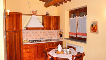 Une cuisine avec des meubles de rangement en bois, une cuisinière à gaz, un évier et une table à manger avec des chaises.