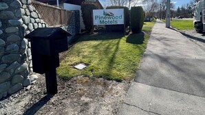 En skylt för Pinewood Motels, med en stenmur och en brevlåda på vänster sida.