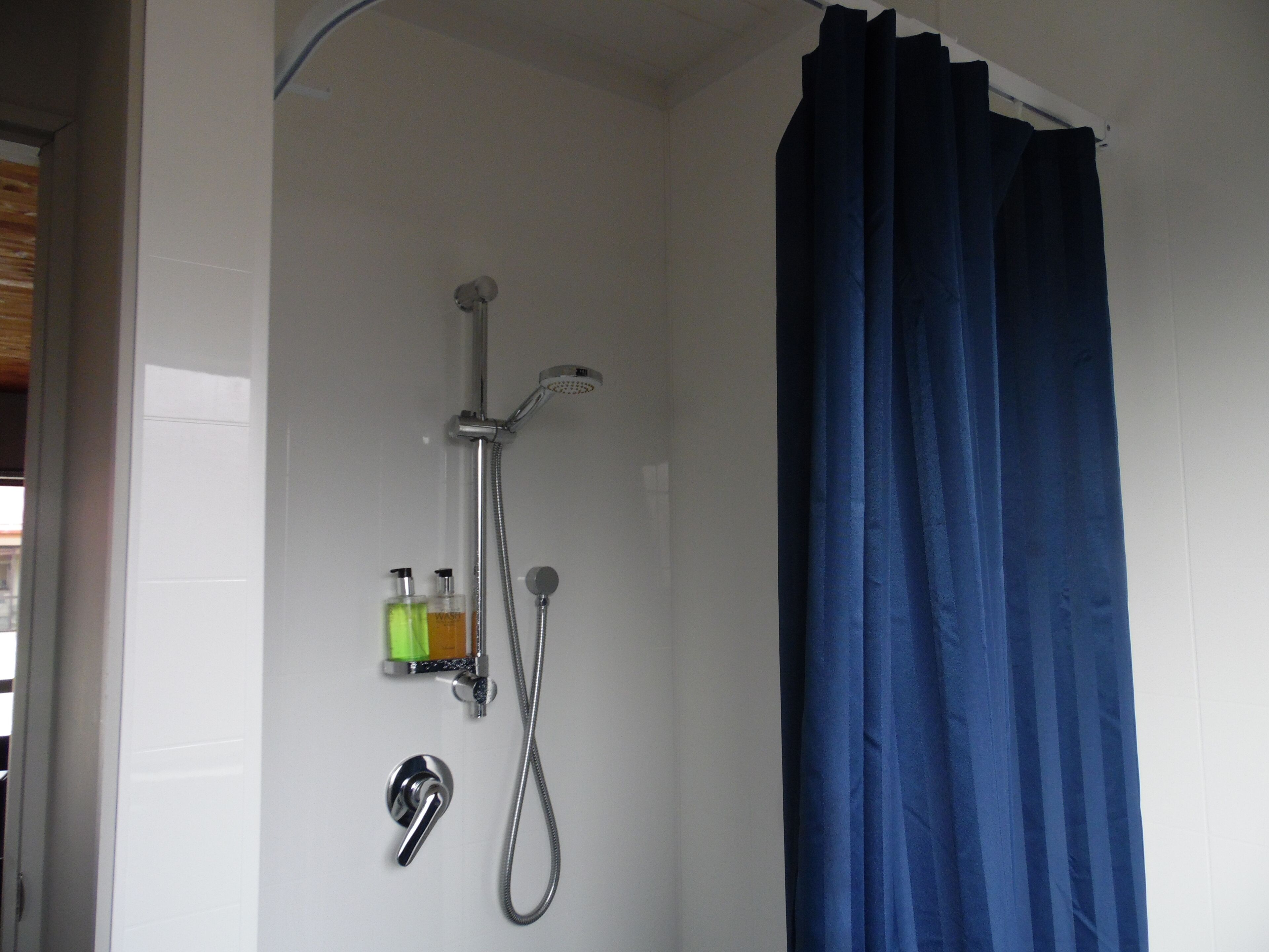 Un baño con ducha, grifo y cortina.