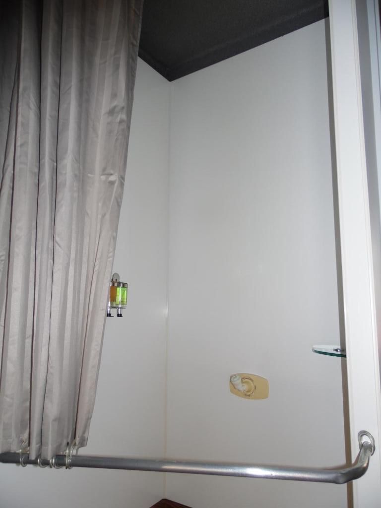 A bathroom with a shower, a towel rack, and a curtain.