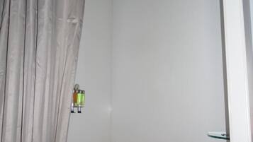 A bathroom with a shower, a towel rack, and a curtain.