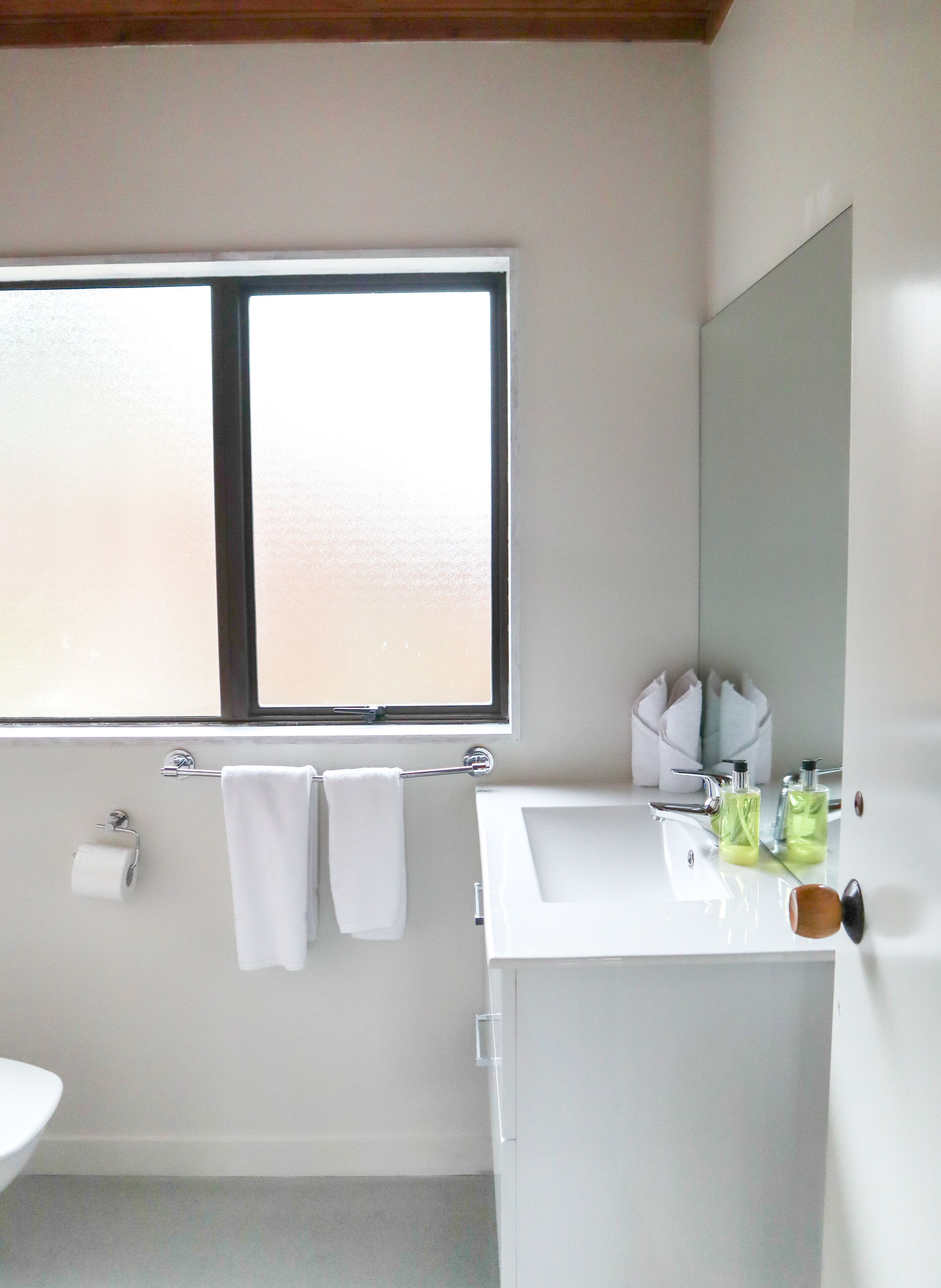 Un baño con ventana, un lavabo y dos botellas de jabón.