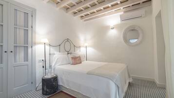 Un dormitorio con cama, lámparas de noche, un espejo redondo y un ventilador de techo.