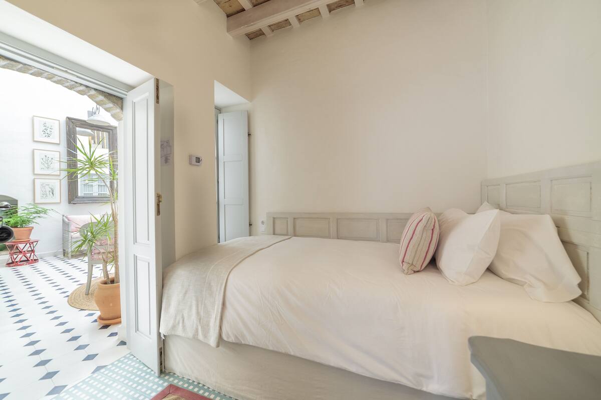 Une chambre à coucher avec un lit, une table de chevet et une porte donnant sur une autre pièce.