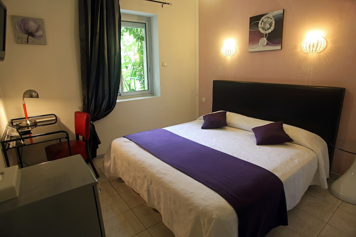 Une chambre à coucher comprenant un lit, un bureau, une chaise, une fenêtre avec des rideaux et des lampes fixées au mur.