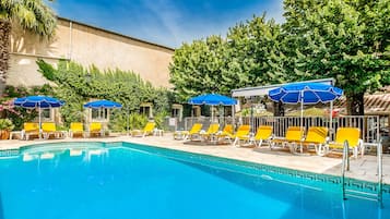 En sÀsongsöppen utomhuspool, parasoller och solstolar