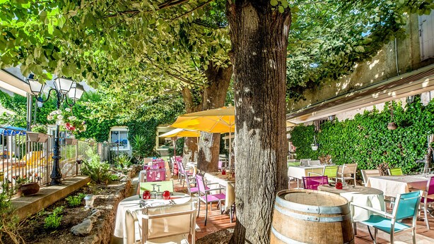 An outdoor dining area with tables and chairs, surrounded by trees and greenery. -  Logis Hôtel Restaurant Résidence (Nissan-lez-Enserune)