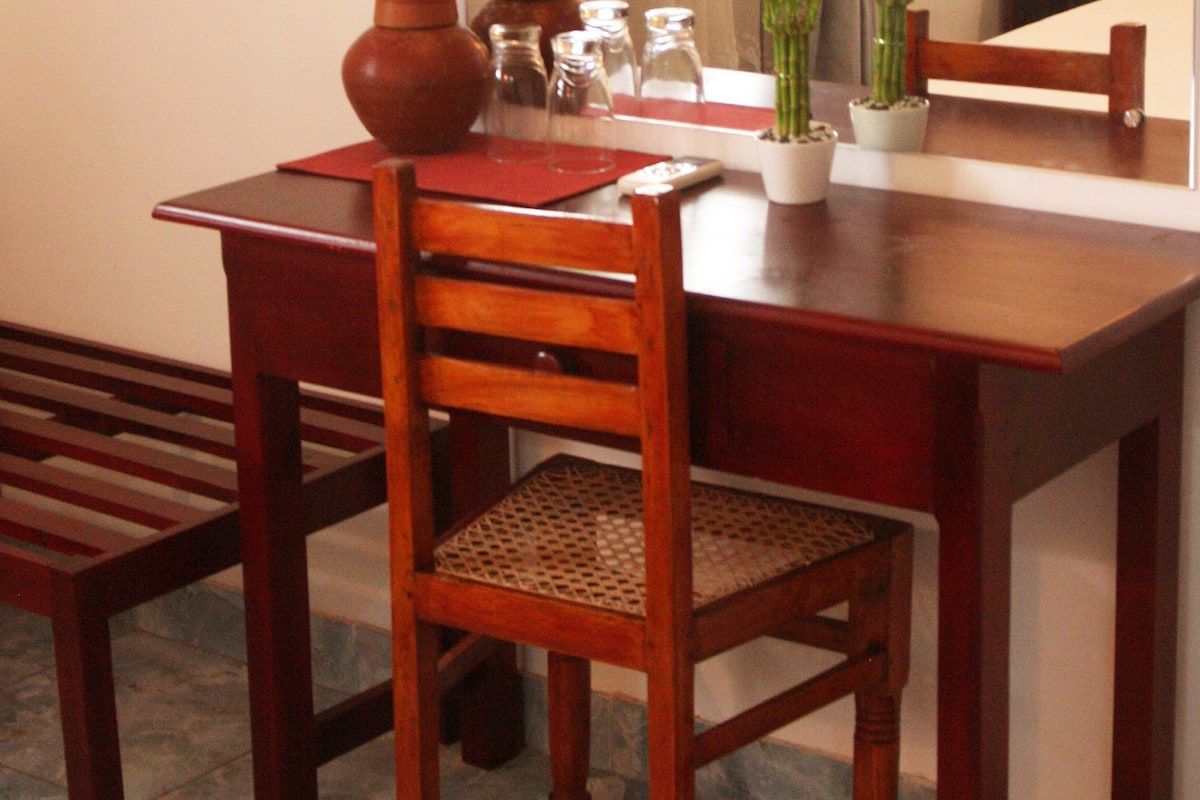 A wooden dining table with a chair, a potted plant, and a vase.