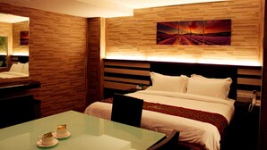 A hotel room with a bed, a bedside table with a phone, a glass table with two cups, and a wall with a wooden panel and a painting. - Hotel Time Nilai (Nilai)