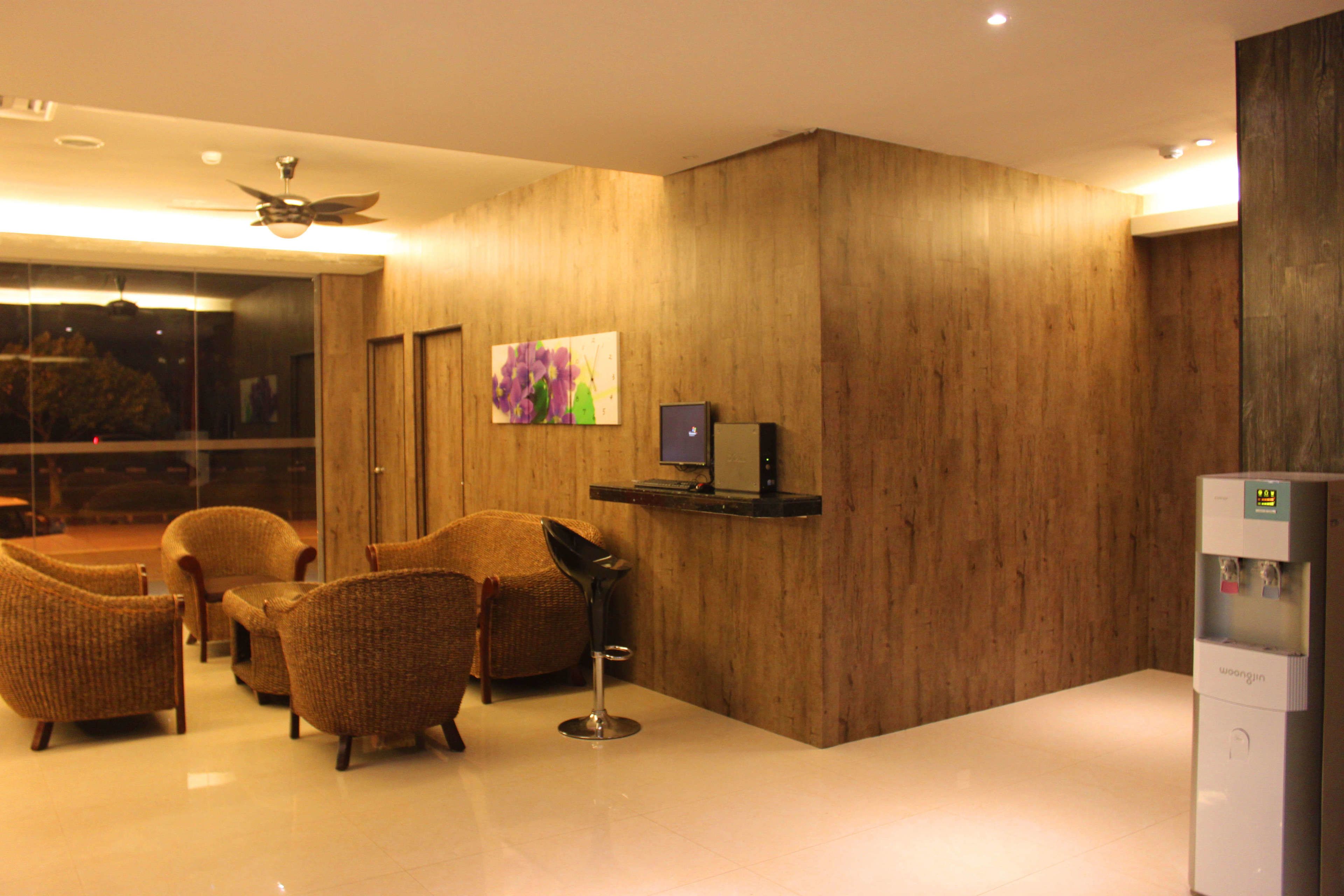 A hotel lobby with a wooden wall, a ceiling fan, a TV, and a water dispenser.