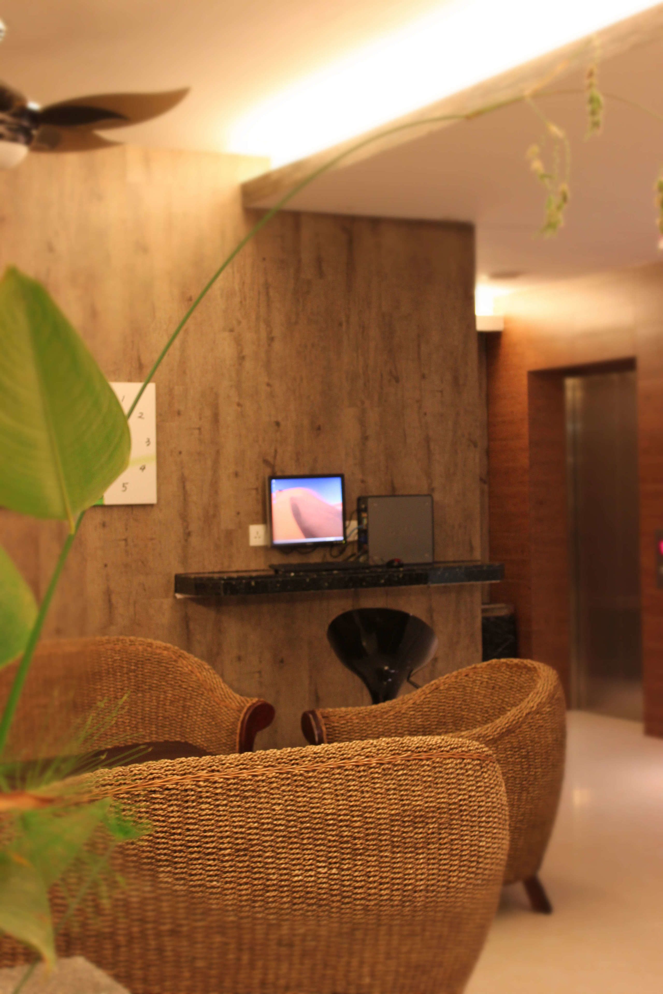 Un interior moderno con una pared de madera, un televisor de pantalla plana, mobiliario de mimbre y un ventilador de techo.
